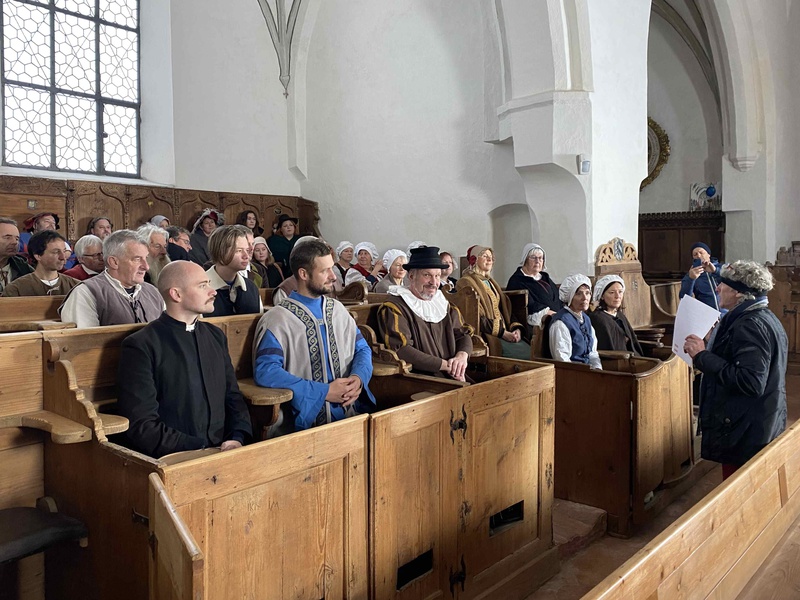 In der St. Martinskirche in Memmingen spielen Laienschauspieler:innen und Mitglieder aus Heimatvereinen als Statist:innen eine Szene mit dem Prediger Christoph Schappeler. Foto: Karl Milz